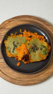 Moong Dal Shakshuka topped with curry leaf tadka in a skillet