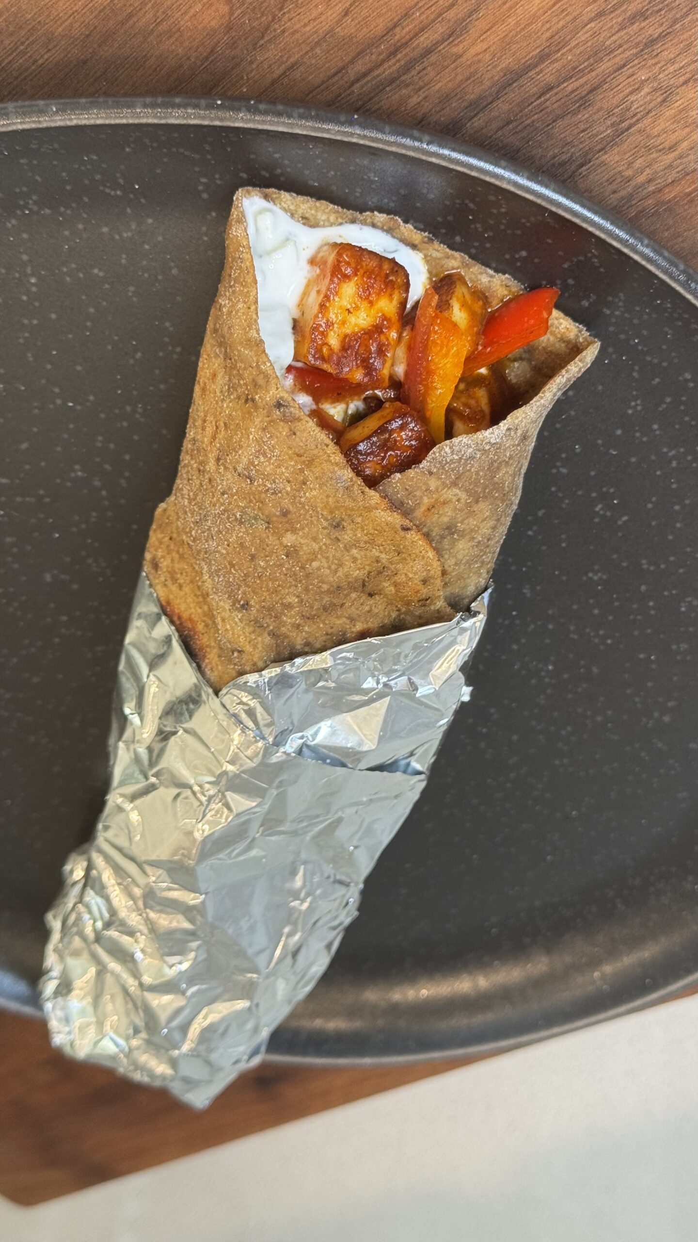 A freshly rolled high-protein beetroot paneer wrap cut in half on a plate, featuring a bright pink whole-wheat flatbread and a creamy vegetable filling.