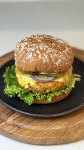 High-protein paneer and sprout burger layered with melted cheese, fresh lettuce, tomato, red onion, and creamy dill sauce in a toasted burger bun